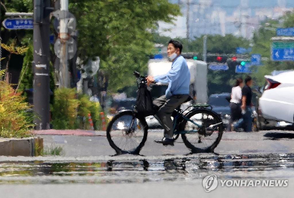 폭염에 이글거리는 도로 (광주=연합뉴스) 조남수 기자 = 전국 대부분 지역에 폭염 특보가 발효된 3일 광주 서구 치평동에서 시민들이 강렬한 햇빛에 달구어져 아지랑이가 피어오르는 도로를 지나고 있다. 2025.7.3 iso64@yna.co.kr